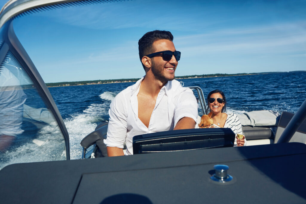 young-man-steering-boat-with-woman-in-background | Find Boats like this at Best Selling Boats - Shop and buy used or new boats at Best Selling Boats.